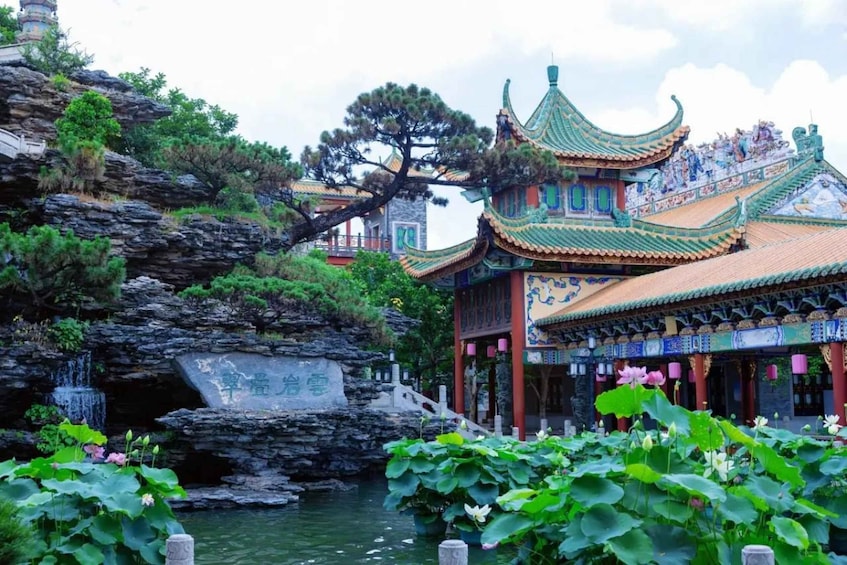 A traditional Chinese building with ornate architecture, a rock garden, and a pond with lotus flowers. 5