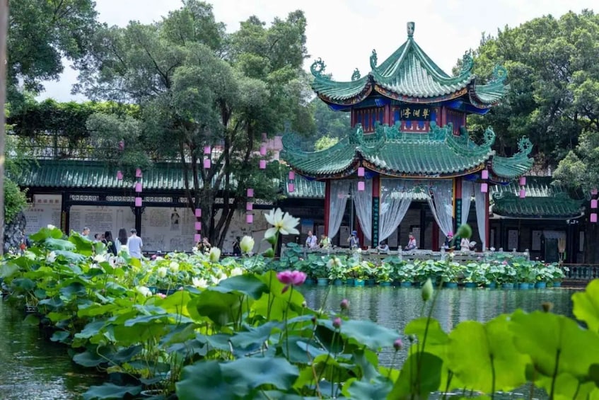 A traditional Chinese pavilion with ornate green roofs and white walls, surrounded by a lotus pond and trees. 3