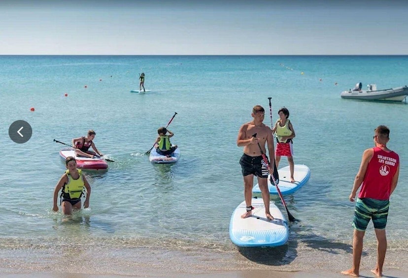 People paddleboarding on a calm sea with a boat in the background. 1