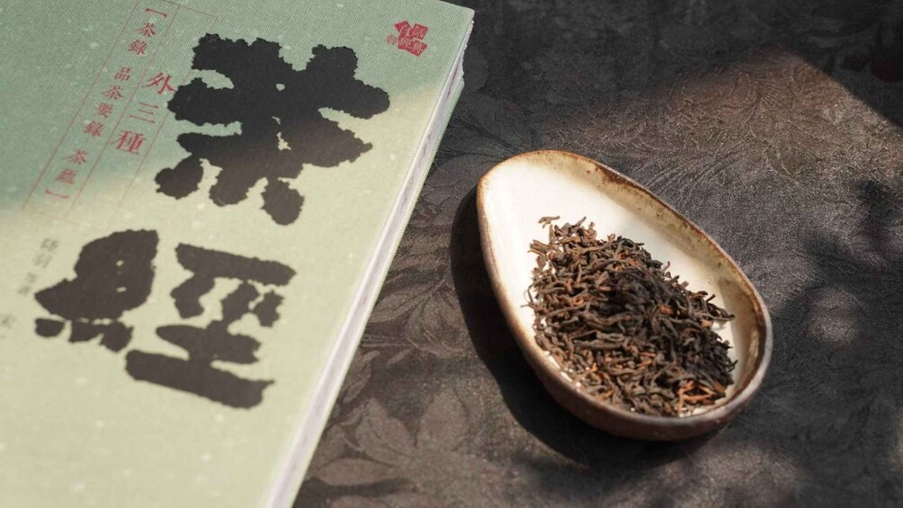 A book with Chinese characters and a ceramic bowl filled with tea leaves. 4