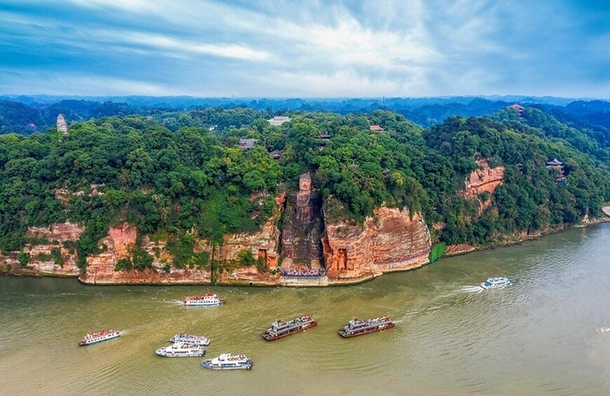 A river with boats, a large rock formation, and dense greenery. 3