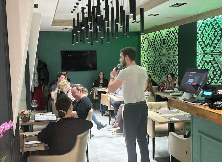 A person speaking at a table in a modern cafe with green walls and pendant lighting. 5