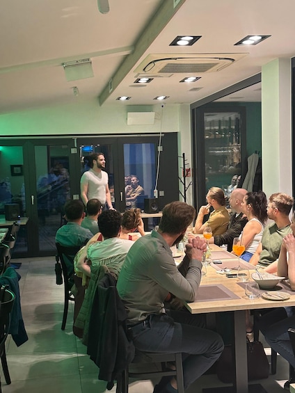 A group of people seated at a table in a modern interior with green walls and recessed lighting. 4
