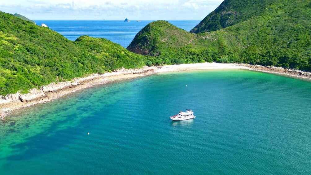 A boat on a turquoise bay surrounded by lush green hills. 1