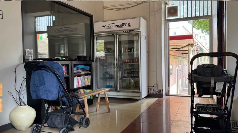 A hallway with a stroller, a baby rocker, and a refrigerator labeled 'The KUNGERS.' 2