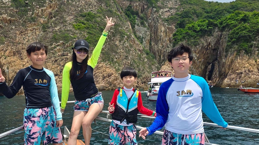 Four people on a boat with a rocky cliff and a boat in the background. 3