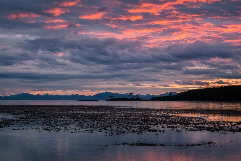 A sunset over a lake with mountains in the background. 1