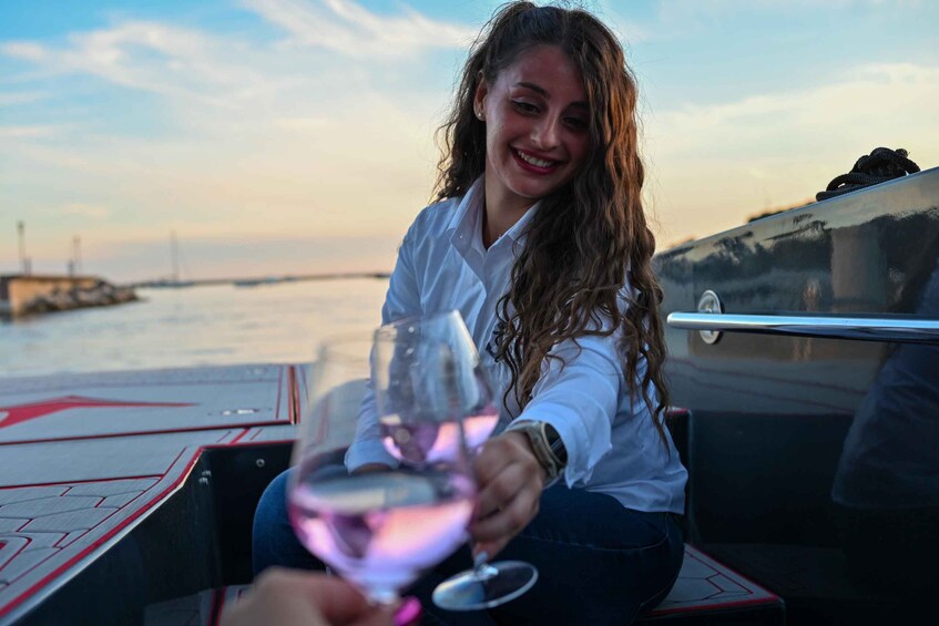 A person holding a wine glass on a boat with a water body and a bridge in the background. 1