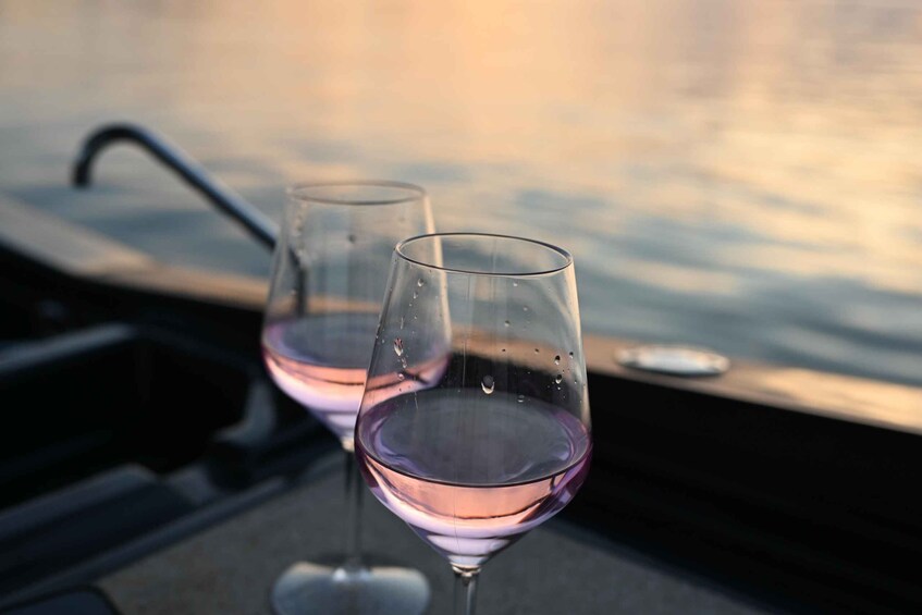Two wine glasses on a table with a body of water in the background. 5