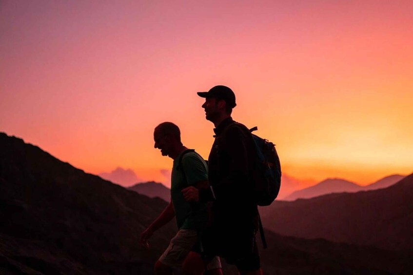 Two hikers walking on a mountain trail during sunset. 4