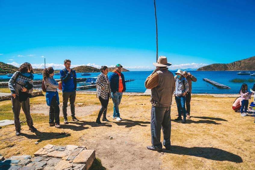 A group of people standing on a beach with a clear blue sky and calm sea in the background. 3