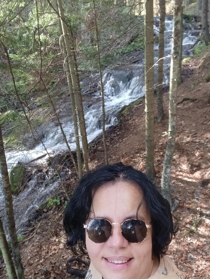 A person in a forest with a waterfall in the background. 2