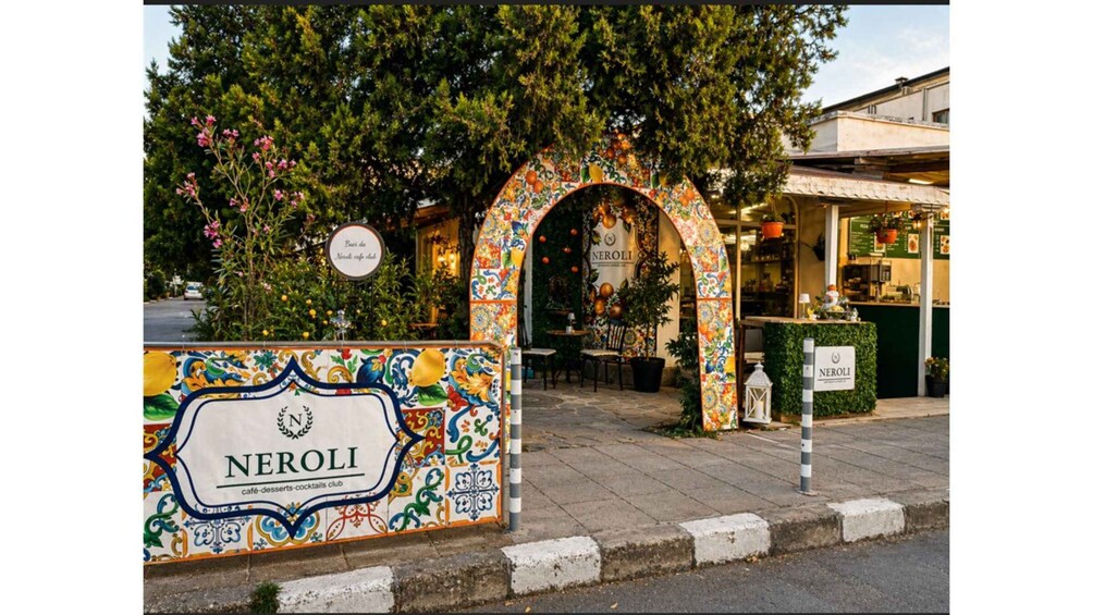 A café entrance with a colorful archway and a sign reading 'NEROLI café-desserts-cocktails club.' 2