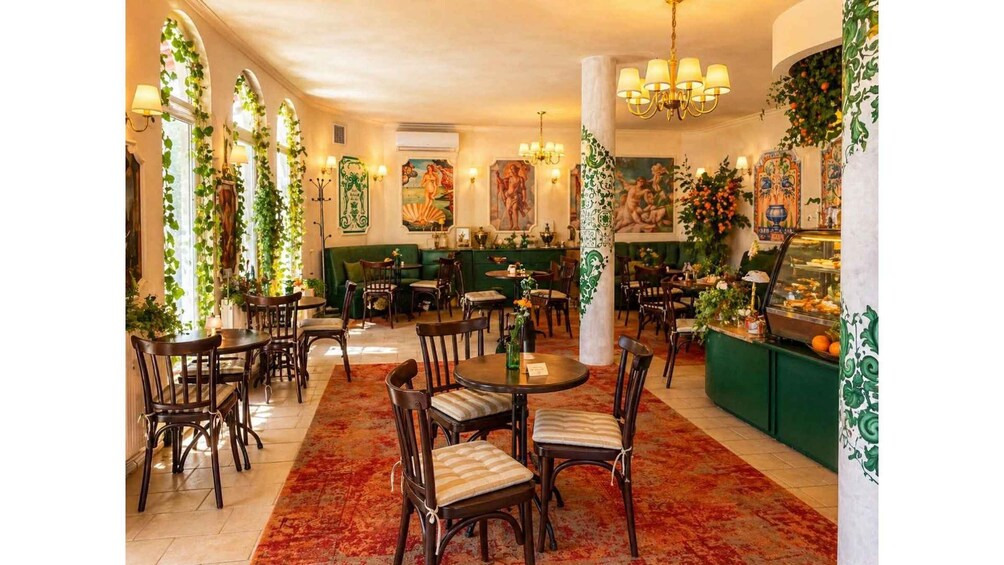 A restaurant interior with round tables, chairs, green walls, and decorative plants. 3