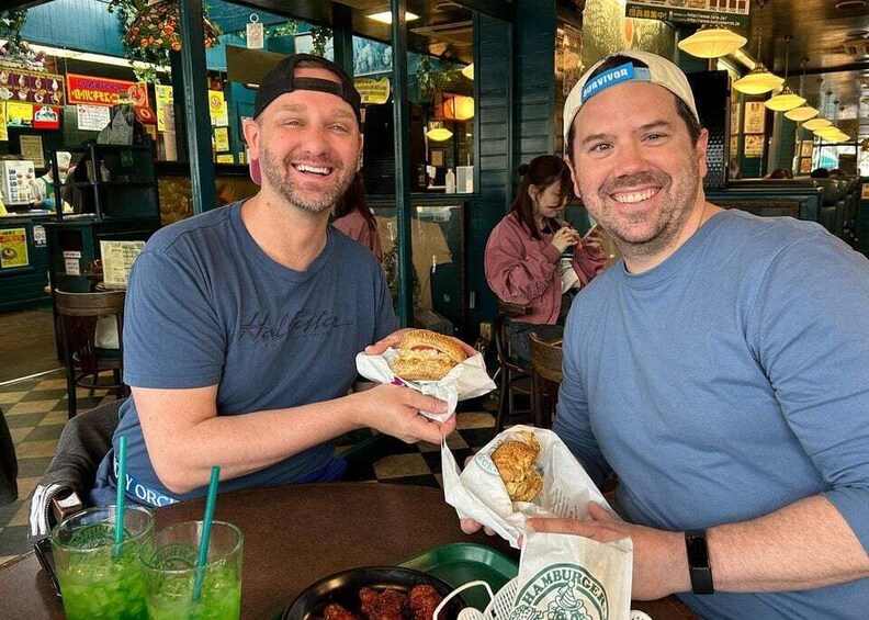 Two people sitting at a table in a restaurant, holding food wrapped in paper. 5