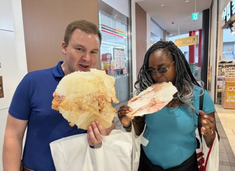 Two people holding large pieces of food in a shopping area. 4