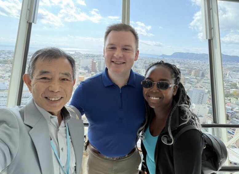 Three people in a high-rise building with a cityscape view. 3