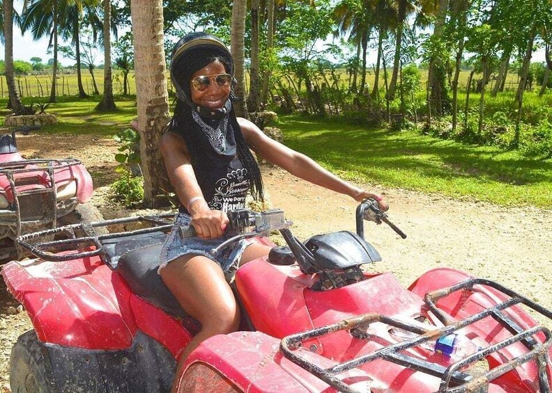 A person riding a red ATV in a rural setting with trees and open fields. 5