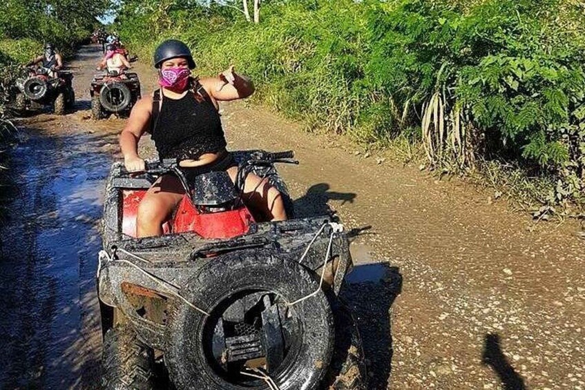 A person on a quad bike on a dirt path surrounded by greenery. 2