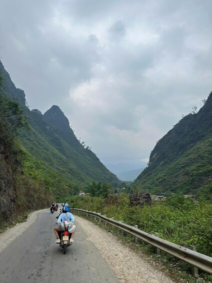 A motorcycle on a winding mountain road with lush greenery on both sides. 5