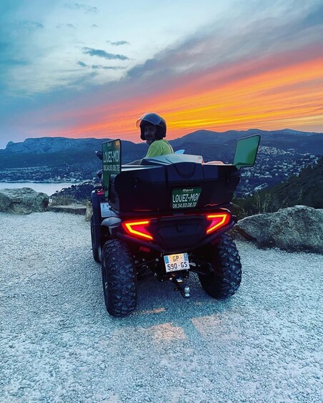 A person riding a quad bike on a gravel path with a sunset in the background. 2
