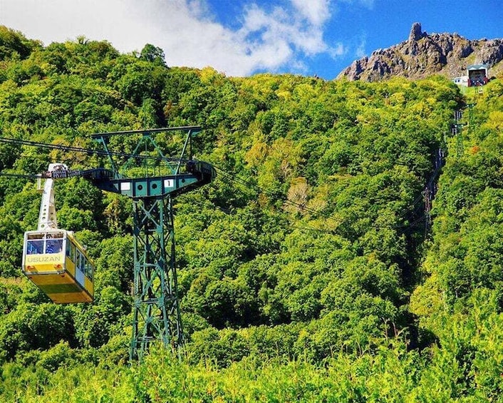 A cable car system with a cable car labeled 'USUZAN' suspended over a lush green forested mountain. 5