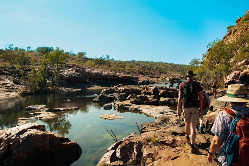 A rocky riverbank with hikers walking along it. 3