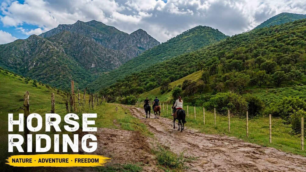 Horse riders on a dirt path through a mountainous landscape. 1