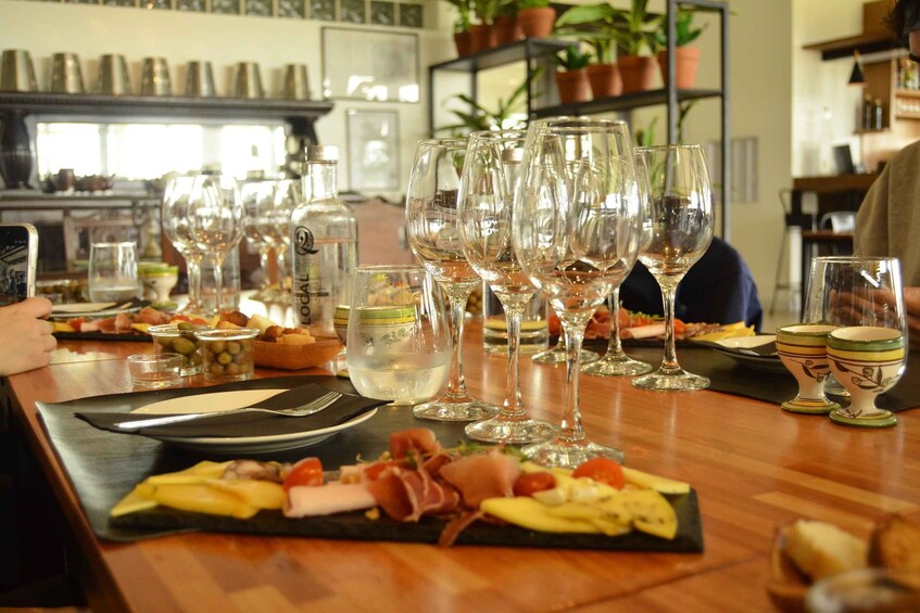 A restaurant setting with a wooden table, wine glasses, and a variety of food items. 1