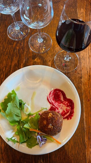 A plate with a salad, a heart-shaped food item, and a glass of red wine on a wooden table. 2