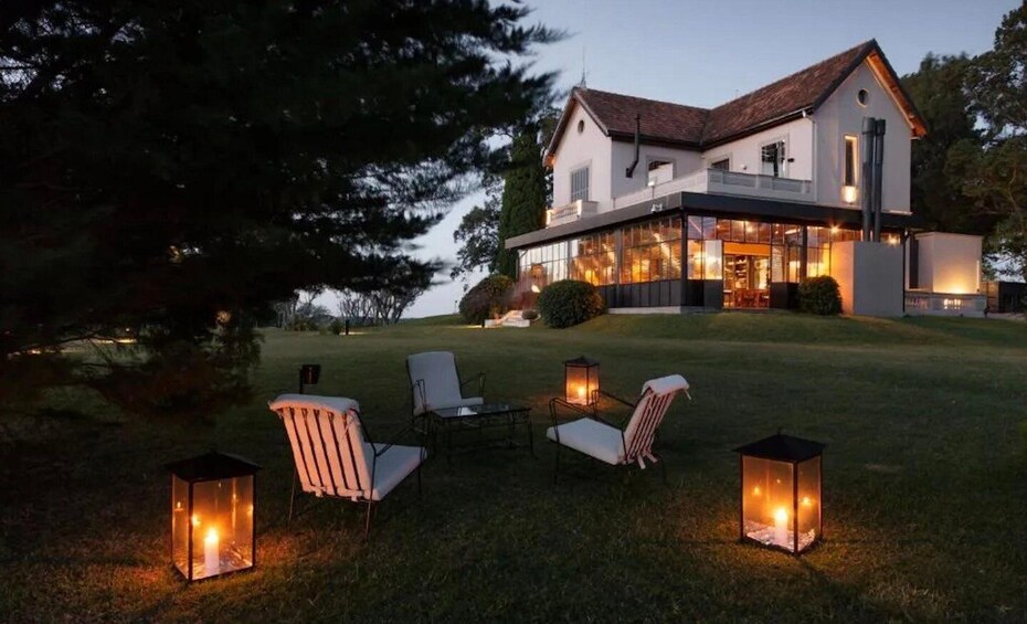 A modern house with a large glass facade, outdoor seating, and lanterns. 3