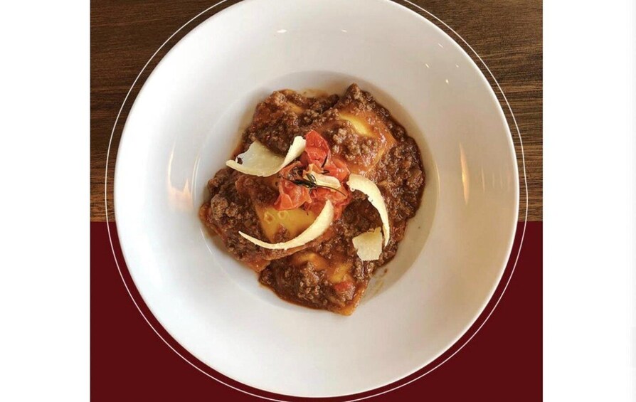 A white plate with a meat dish, garnished with tomato slices and onion rings. 3