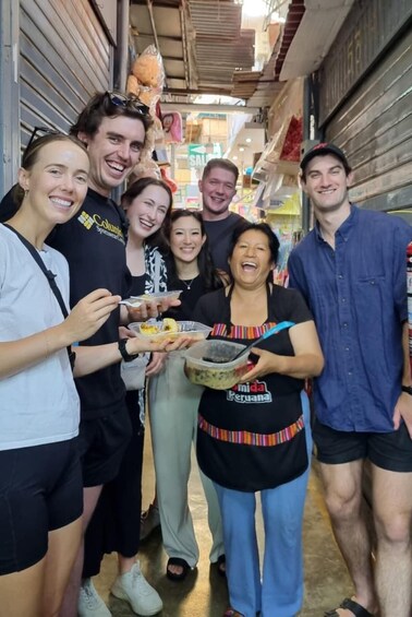 A group of people in a narrow alleyway with shops on either side. 1