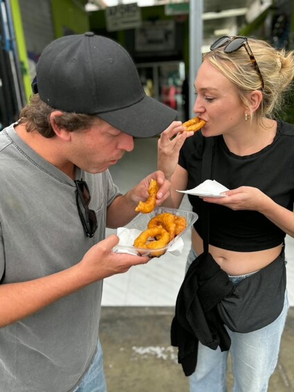 Two people eating doughnuts outdoors. 5