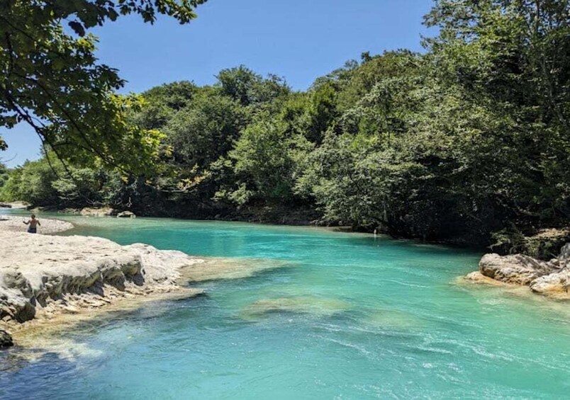 A turquoise river surrounded by dense greenery and rocky outcrops. 1