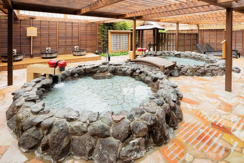 A traditional Japanese onsen with stone baths, wooden structures, and tiled flooring. 3