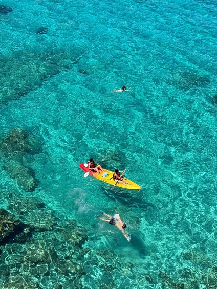 A kayaker and a swimmer in clear turquoise water. 1