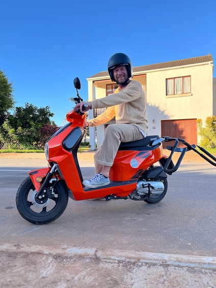 A person on a red scooter parked on a street. 1