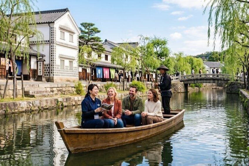 A group of people in a wooden boat on a calm river, surrounded by traditional buildings and a stone bridge. 1