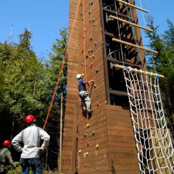 A person climbing a wooden structure with climbing holds. 2