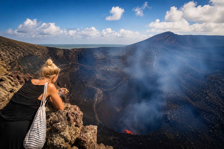 A person observing a volcanic crater with smoke and lava. 1