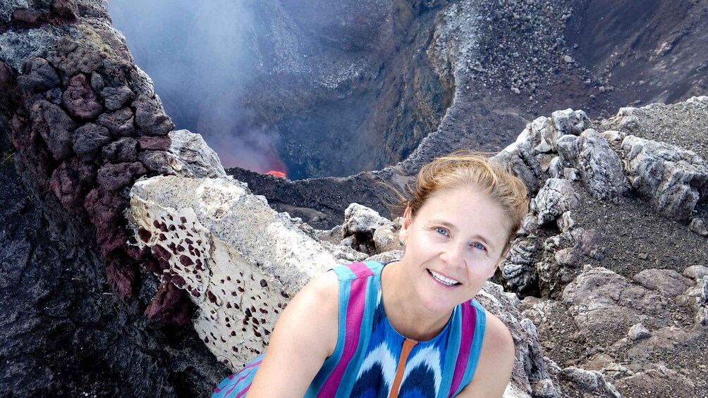 A person sitting on a rocky outcrop with a volcanic landscape in the background. 4