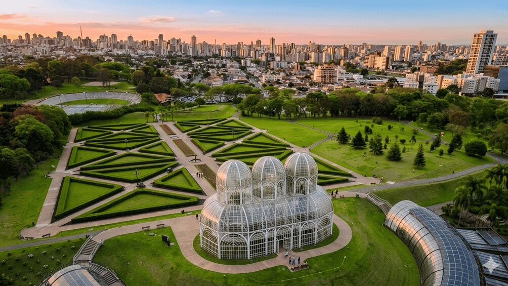 A cityscape with a large botanical garden featuring geometric landscaping and a glasshouse structure. 5