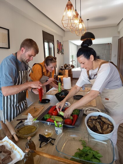 A group of people preparing food in a kitchen with various vegetables and cooking utensils on the counter. 4