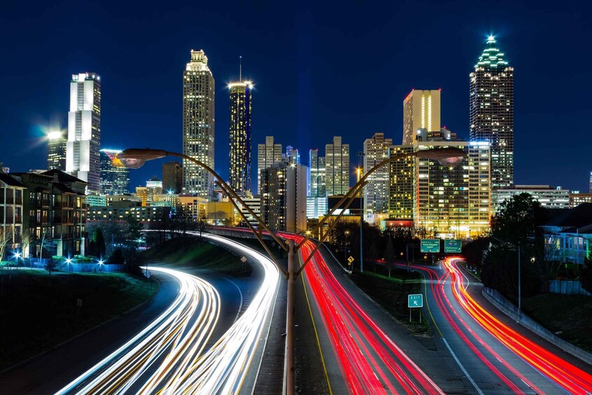 A city skyline at night with illuminated buildings and a multi-lane highway with light trails. 3