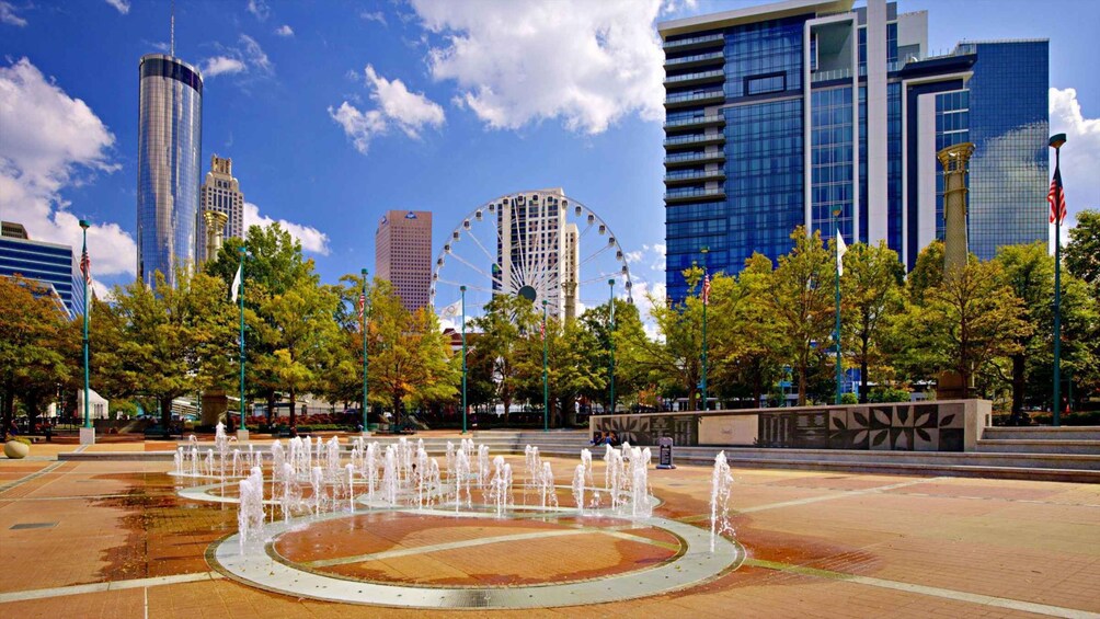 A city plaza with a fountain, trees, and modern buildings including a Ferris wheel. 5