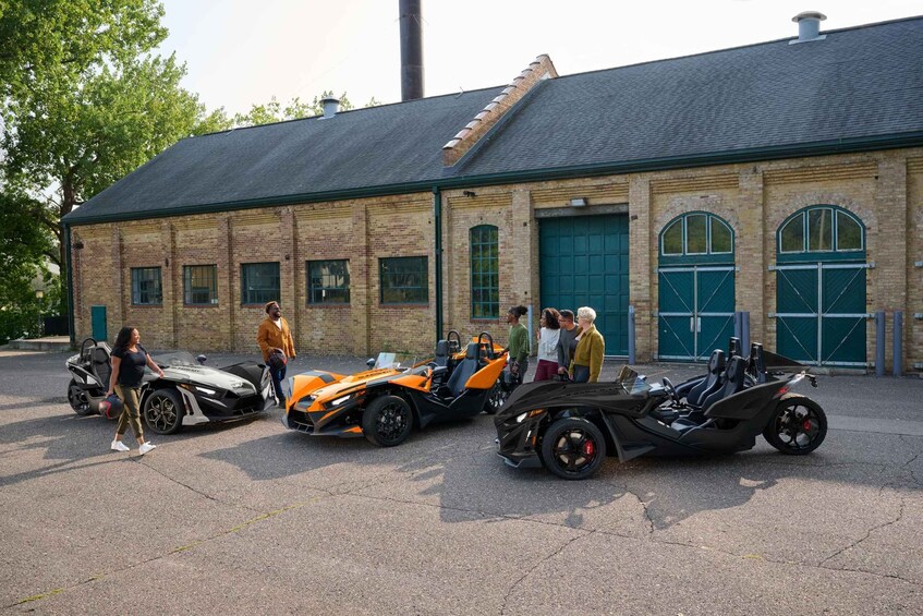 Three sports cars parked in front of a brick building with green doors. 5