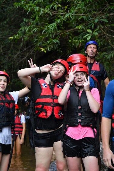 People wearing life jackets and helmets, standing in a forested area. 2
