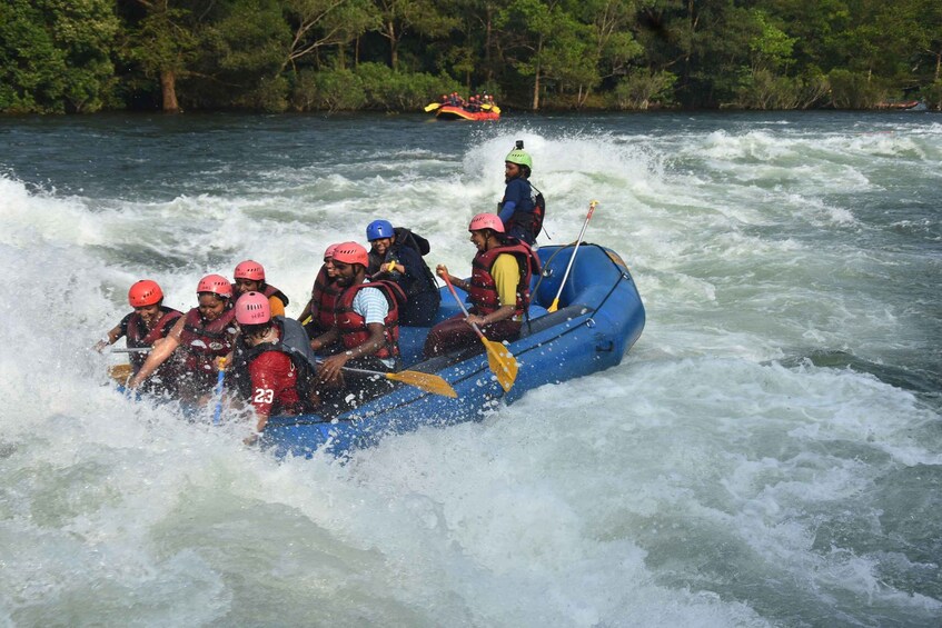 A group of people in a blue raft navigating through a river with white water rapids. 2