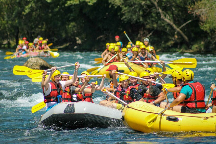 A group of people in yellow inflatable rafts paddling on a river. 3